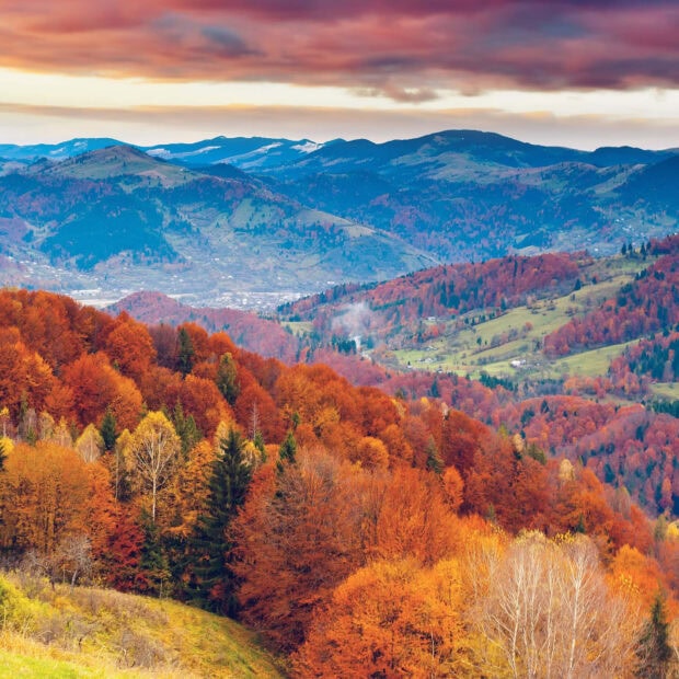 A scenic autumn mountain landscape with rolling hills covered in colorful fall foliage under a dramatic sky is an ideal Fall Ipad Wallpaper