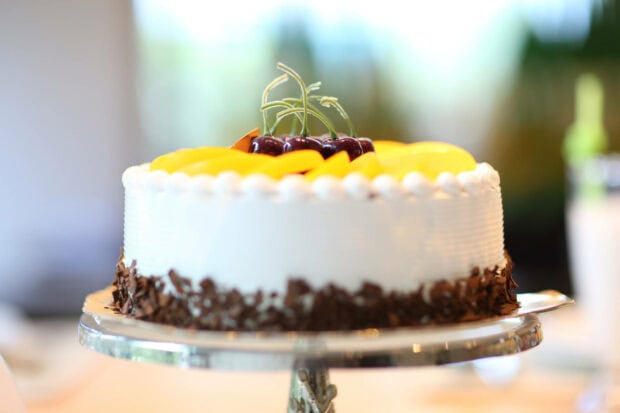 A delicious Birthday Wallpaper featuring a white cake topped with cherries, peaches, and chocolate shavings