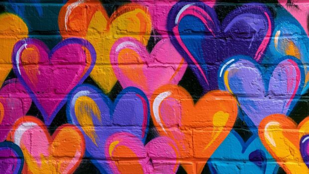 A vibrant graffiti art Heart Wallpaper featuring colorful overlapping hearts painted on a textured brick wall background