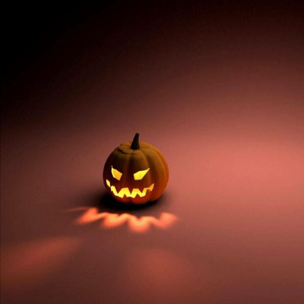 A minimalist Halloween iPad wallpaper showcasing a glowing jack-o'-lantern on a dark background