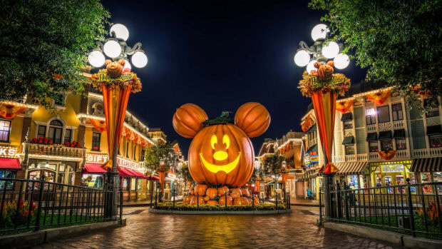 A festive Halloween Macbook wallpaper showing Disneyland decorated with a giant Mickey Mouse pumpkin at night