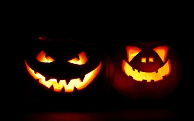 A spooky Halloween Macbook Wallpaper showcasing two glowing jack-o'-lanterns with carved faces in the dark