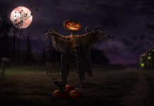 A dark Halloween Macbook Wallpaper showing a scarecrow with a glowing pumpkin head, a black cat, and a haunted house under a full moon