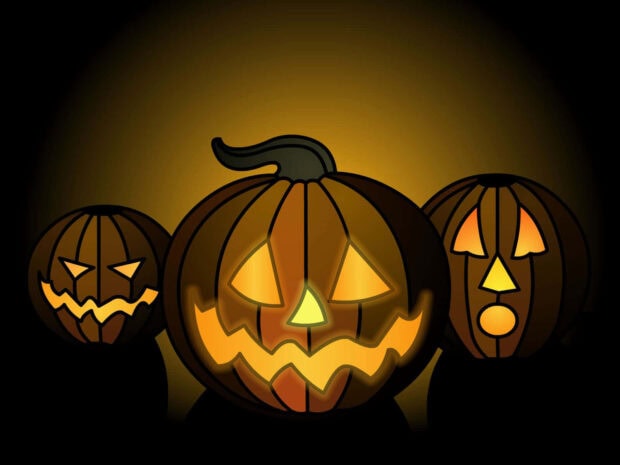 Halloween Macbook Wallpaper depicting three glowing jack-o'-lanterns with carved faces against a dark background