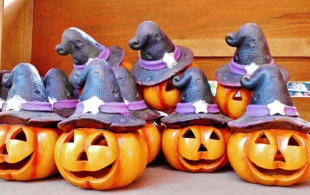 A collection of ceramic Halloween Pumpkin Wallpaper decorations wearing witch hats, arranged closely together