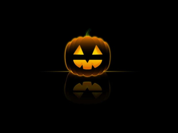 A minimalist Halloween Pumpkin Wallpaper featuring a glowing jack-o'-lantern with a reflection on a dark background