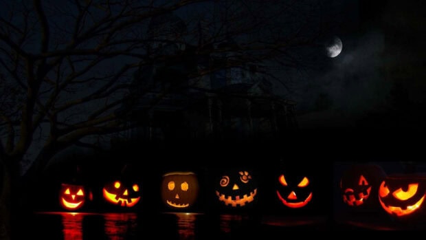 A Halloween Pumpkin Wallpaper showcasing a row of six glowing jack-o'-lanterns against a dark, spooky night background with a haunted house, bare tree, and moon