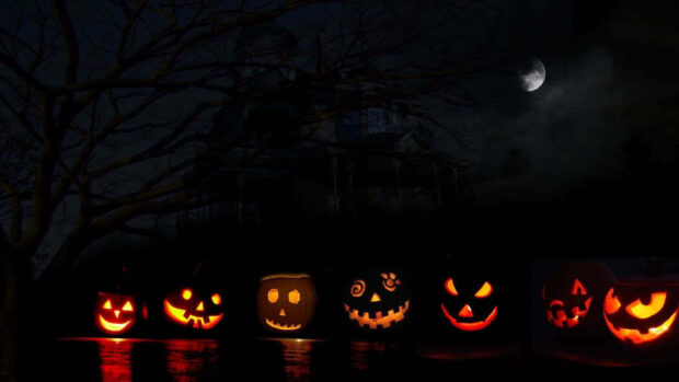 A row of glowing Halloween pumpkin wallpaper in the dark with a spooky house silhouette and moon