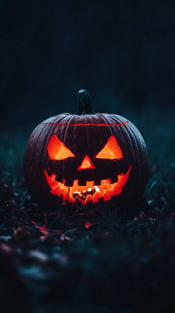 A striking Halloween Pumpkin Wallpaper showcasing a single, intensely glowing jack-o'-lantern with sharp features on dark ground
