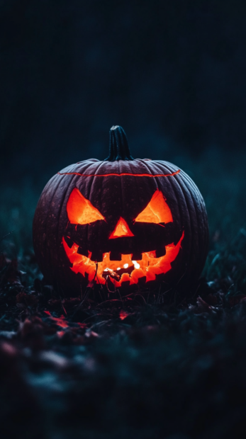 A striking Halloween Pumpkin Wallpaper showcasing a single, intensely glowing jack-o'-lantern with sharp features on dark ground