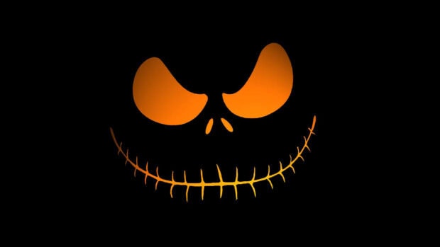 A minimalist Halloween Skeleton Wallpaper showing a glowing orange pumpkin face on a black background