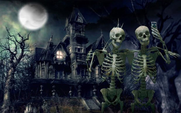 A playful Halloween Skeleton Wallpaper showing two skeletons taking a selfie in front of a haunted house under a full moon