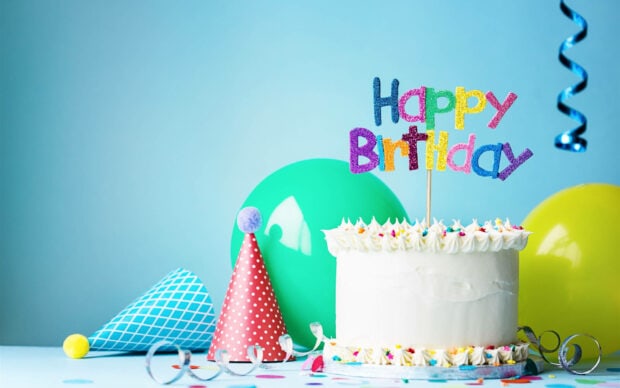 It's My Birthday Wallpaper featuring a white cake with a colorful happy birthday topper, party hats, and green balloons on a light blue background