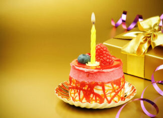 Its My Birthday Wallpaper featuring an elegant individual birthday cake with a lit yellow candle, raspberry, and blueberry on a shimmering gold background with a gift