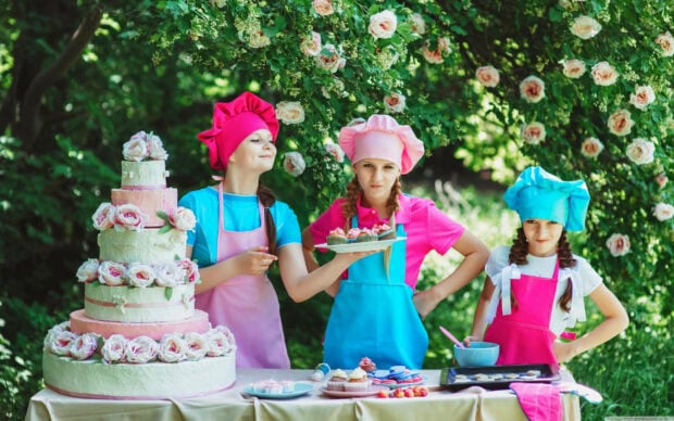 Its My Birthday Wallpaper showing three girls in chef hats with a beautiful tiered cake outdoors