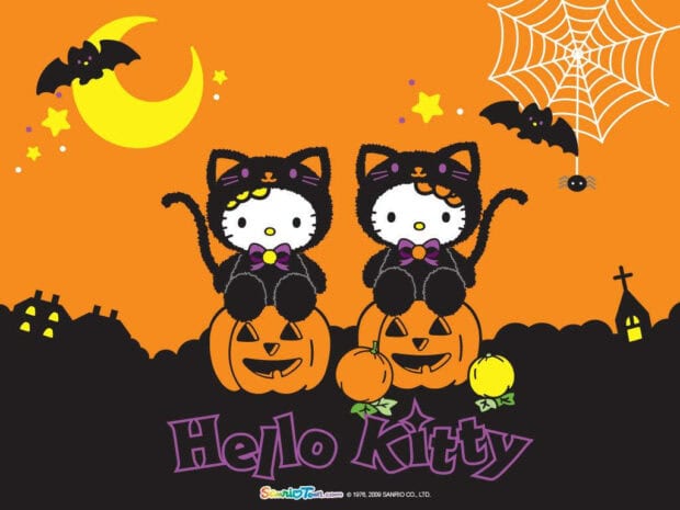 Kawaii Halloween Wallpaper showing two Hello Kitty characters in black cat costumes sitting on pumpkins with bats and a spiderweb