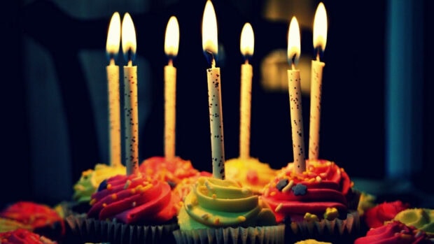 Its My Birthday Wallpaper showing colorful cupcakes with lit candles in a warm, festive setting