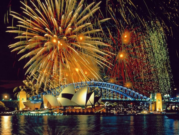 A spectacular New Years Eve Wallpaper featuring the Sydney Opera House and Harbour Bridge illuminated by a grand display of colorful fireworks over the water