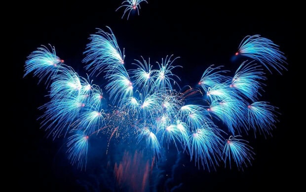 A stunning New Years Eve Wallpaper featuring brilliant blue fireworks exploding across a dark night sky