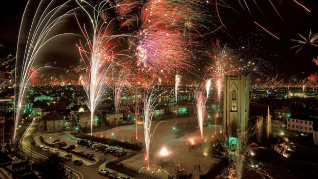 An aerial New Years Eve Wallpaper showing a city celebrating with multiple fireworks bursts across the skyline
