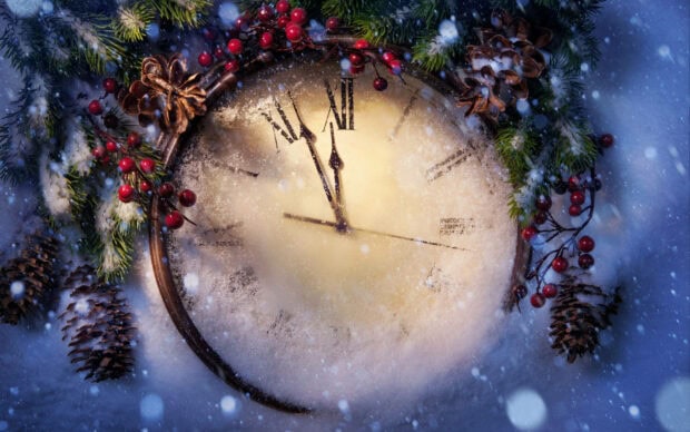 A festive New Years Eve wallpaper featuring an antique clock covered in snow, surrounded by pine branches and red berries