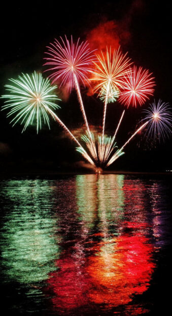New Years Eve Wallpaper featuring colorful fireworks exploding over water with vivid reflections below
