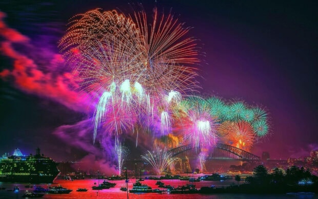 An amazing New Years Eve Wallpaper capturing a spectacular fireworks display over Sydney Harbour Bridge and opera house with boats