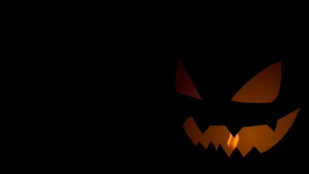 A dark minimalist Pokemon Halloween wallpaper showing a glowing jack-o'-lantern face in the shadows