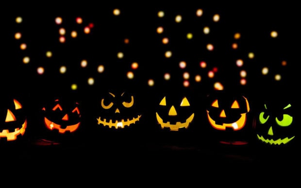 Preppy Halloween Wallpaper featuring a row of glowing jack-o'-lanterns with festive carved faces and bokeh lights