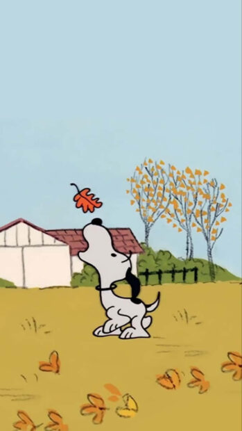 An adorable Snoopy Fall Wallpaper depicting Snoopy looking up at a falling autumn leaf with a small house and fall trees in the background