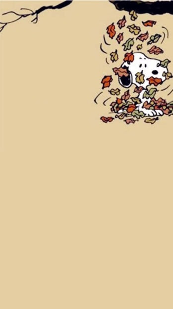 A cute Snoopy Fall Wallpaper showing Snoopy peeking out from a large pile of colorful autumn leaves against a subtle beige background