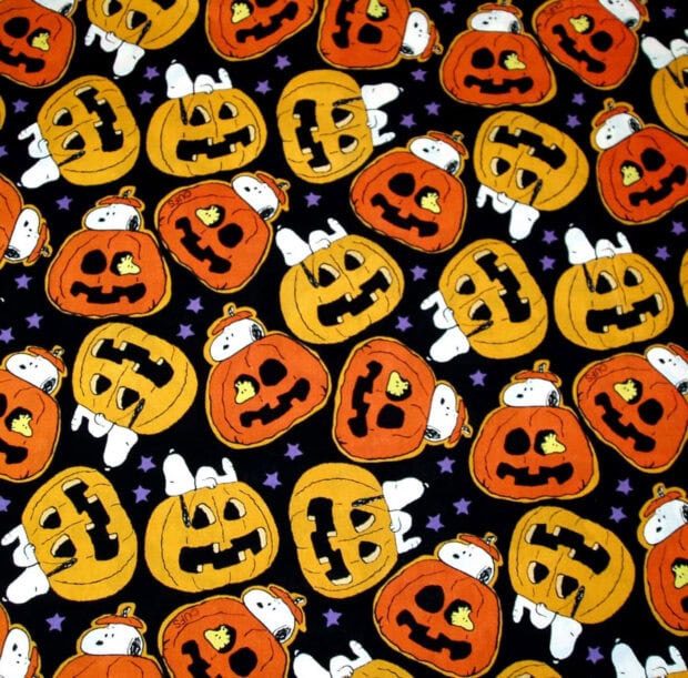 A busy Snoopy Fall Wallpaper featuring a repeating pattern of Snoopy peeking out from various carved pumpkins against a dark background with small purple stars