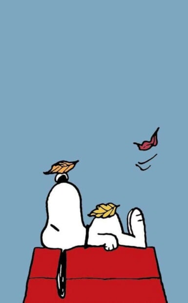 A peaceful Snoopy Fall Wallpaper showing Snoopy sleeping soundly on his red doghouse with autumn leaves falling around him