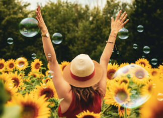 A joyful person with a straw hat in a field of vibrant sunflowers with floating bubbles, perfect for a Summer Aesthetic Wallpaper