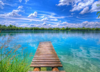 A serene Summer Vibes Wallpaper with a wooden pier extending into a clear blue lake under a bright sky