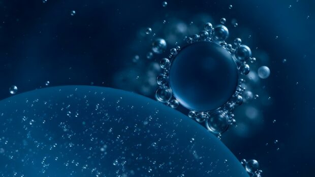 An Abstract Digital Wallpaper Blue showcasing a mesmerizing macro shot of liquid with numerous bubbles, including a prominent circular cluster of bubbles, set against a deep blue background. This high-quality image provides a unique visual for desktop