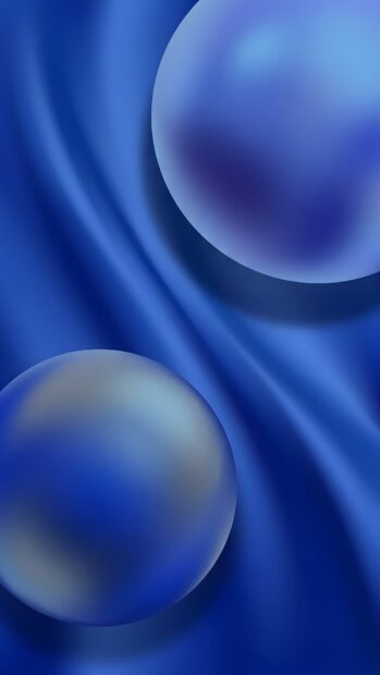 This abstract digital wallpaper features two smooth, translucent blue spheres floating above a wavy dark blue fabric texture, creating a serene and modern look. It's a perfect abstract digital wallpaper blue background for mobile devices