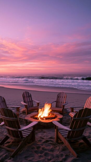 A cozy beach wallpaper depicting a bonfire surrounded by Adirondack chairs on the sand, with a beautiful pink and purple sunset sky