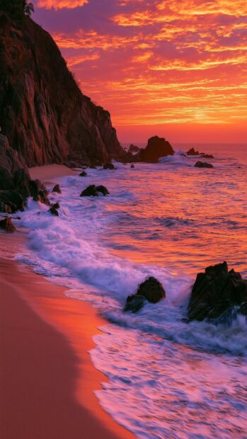 A stunning beach wallpaper featuring a dramatic sunset with orange and pink skies over ocean waves crashing against a rocky cliff