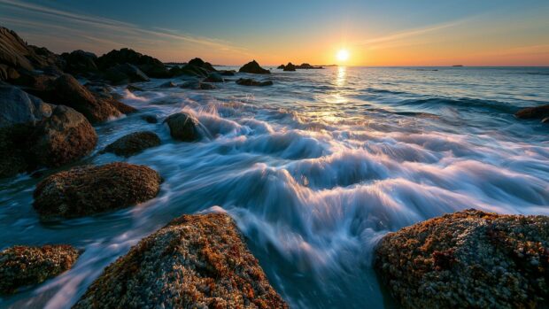 A dynamic beach wallpaper showing waves crashing over a rocky coastline during a beautiful sunset