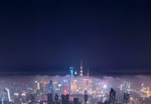 An breathtaking aerial City Wallpaper showcasing a bustling city at night, with illuminated highways forming intricate patterns and towering skyscrapers piercing through the misty sky