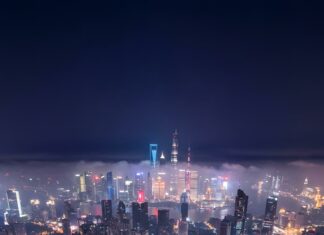 An breathtaking aerial City Wallpaper showcasing a bustling city at night, with illuminated highways forming intricate patterns and towering skyscrapers piercing through the misty sky
