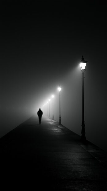 Dark wallpaper showing a lonely person walking down a foggy street lined with glowing streetlights