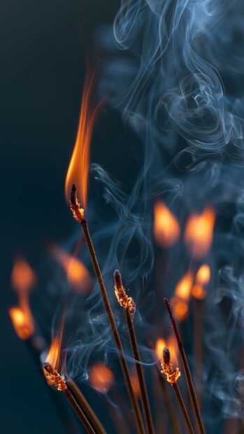 A vertical fire wallpaper showcasing multiple burning incense sticks with small orange flames and swirling white smoke