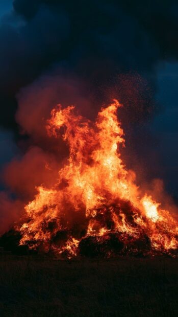 An epic fire wallpaper depicting a huge bonfire burning intensely with smoke against a dark blue sky