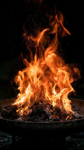 An intense fire wallpaper showing a large fire burning with sparks in a metal brazier against a dark background