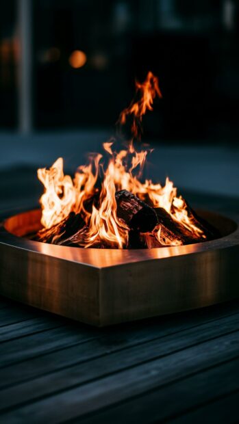 A cozy fire wallpaper featuring a rustic fire pit with burning logs on a dark wooden deck