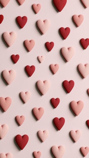A beautiful Hearts Wallpaper featuring a repeating pattern of small red and light pink textured hearts on a soft pink background