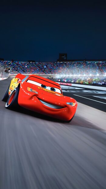A vibrant Lightning Mcqueen Wallpaper showing the red race car speeding on a dark track with stadium lights in the background