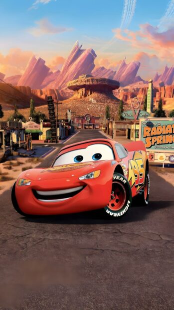 A vibrant Lightning Mcqueen Wallpaper featuring the car smiling in front of the iconic Radiator Springs landscape